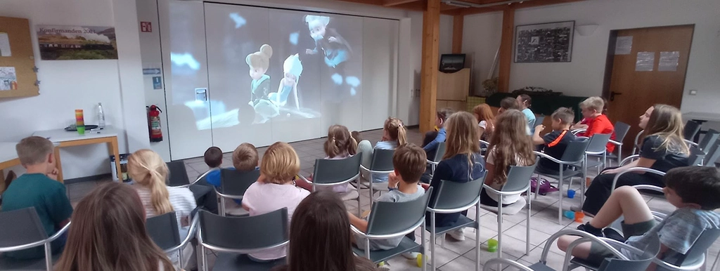 Die Kinder sehen auf einer großen Leinwand eine Film.