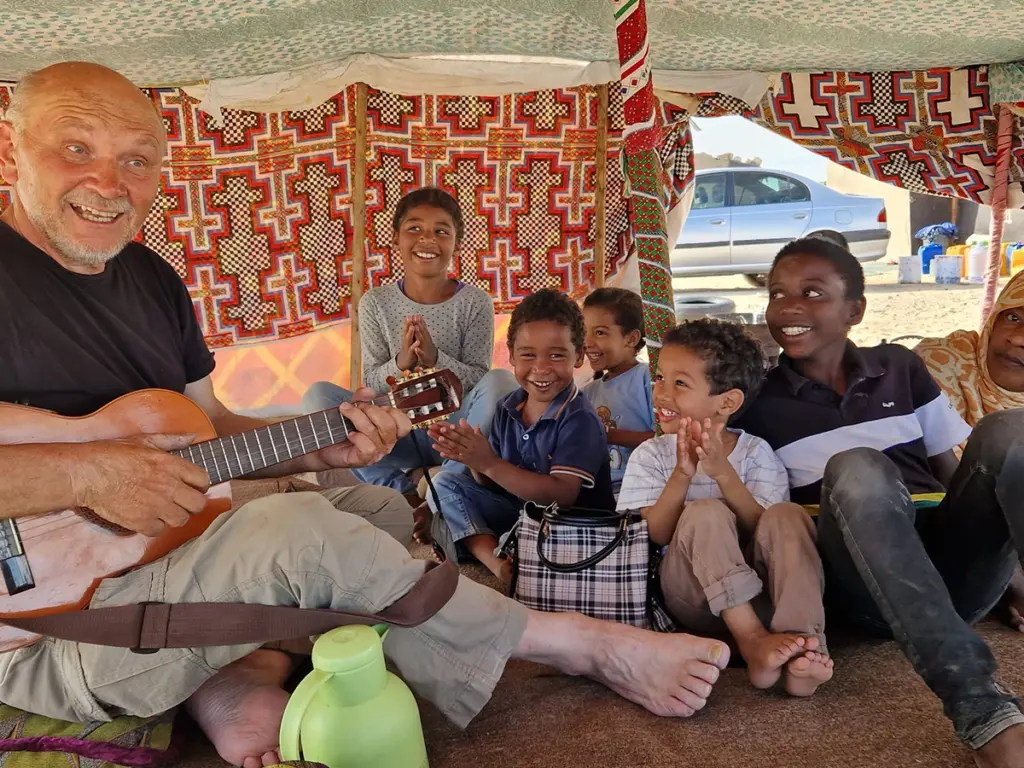 Kinder schauen begeistert auf Pfarrer Roller, der Gitarre spielt