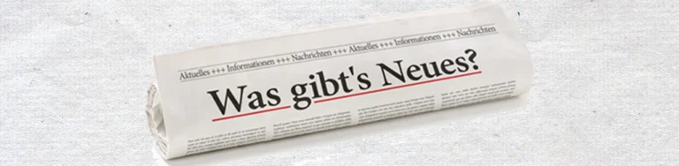 Zusammengerollte Zeitung mit dem Text "Was gibt's Neues?"