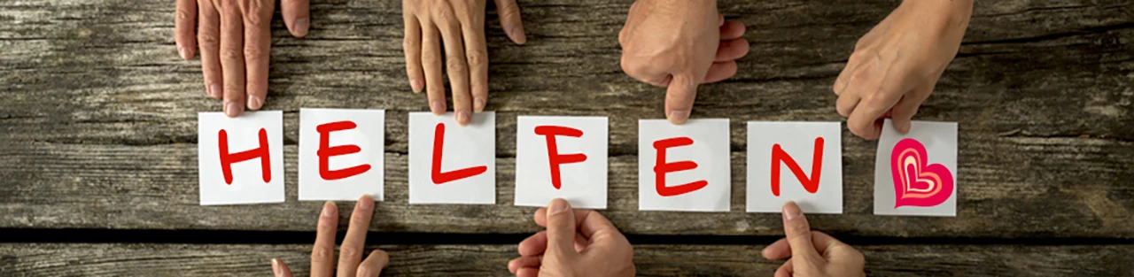 Viele Hände halten Zetteln mit Buchstaben, die zusammen das Wort "Helfen" und ein Herz ergeben.