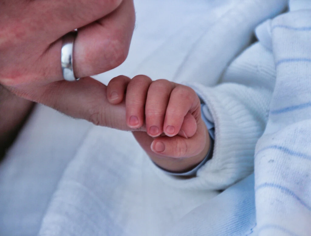 Eine Babyhand hält einen beringten Finger