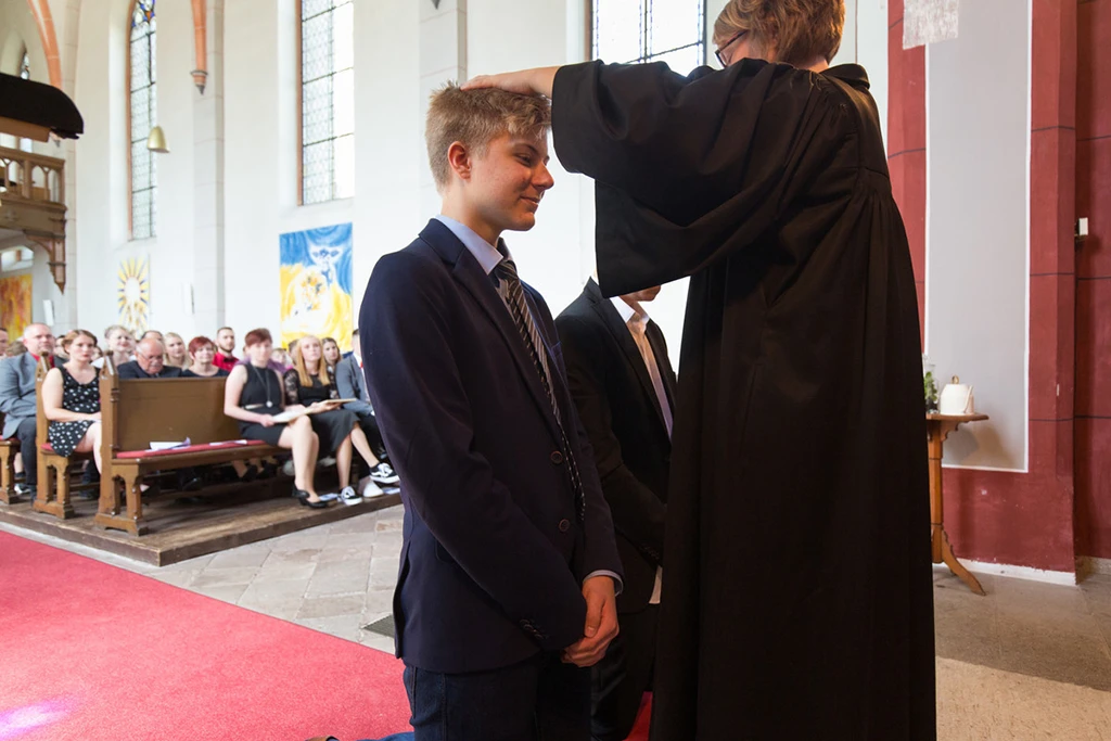 Die Pfarrerin erteilt einem jungen Mann den Segen.