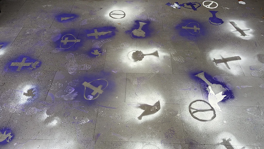 Die gesprühten Symbole: Friedentauben, das Peace-Zeichen, das christliche Kreuz und ein Baum